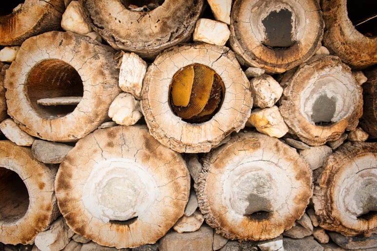 Palm tree trunks cut and hollowed out, then stacked.